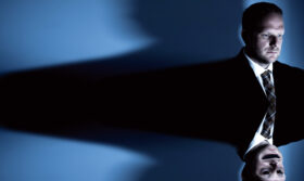 A man in a suit with a distorted reflection.