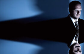 A man in a suit with a distorted reflection.