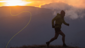 A lone figure running along a fell with the sun setting behind.