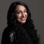 A smiling Seeta against a grey backdrop