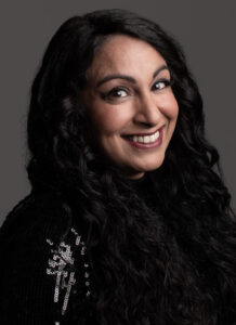 A smiling Seeta against a grey backdrop