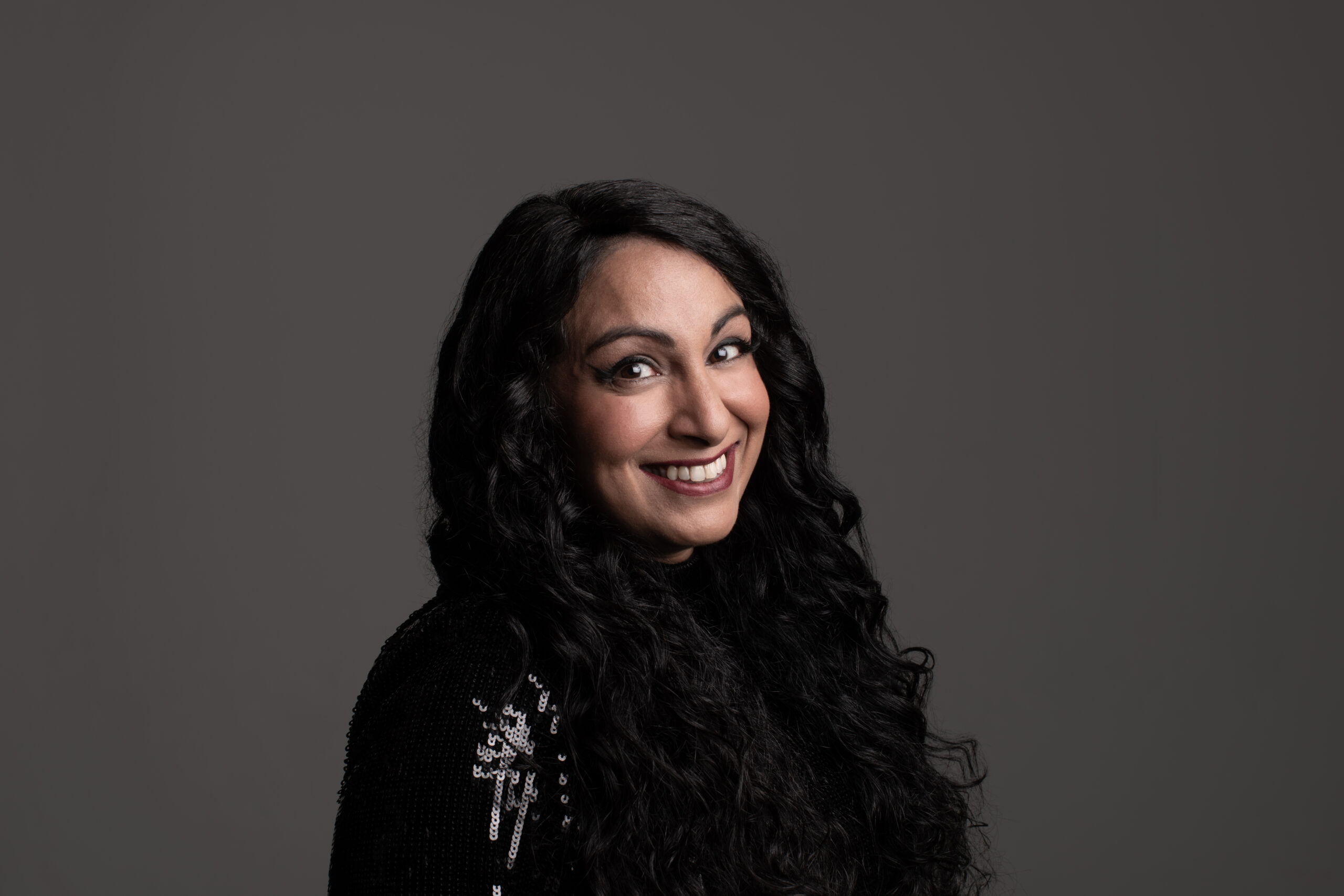 A smiling Seeta against a grey backdrop