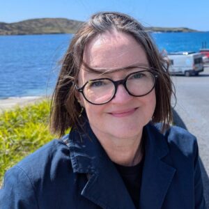 A smiling Deborah on the edge of a breezy lake