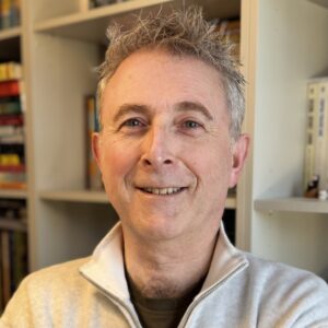 Richard's smiling selfie in front of bookshelves