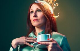 A woman holding a cup and saucer wearing a crown with flames coming out