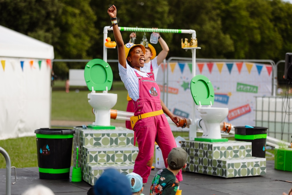 A woman cheering in front of two toilets on a stage