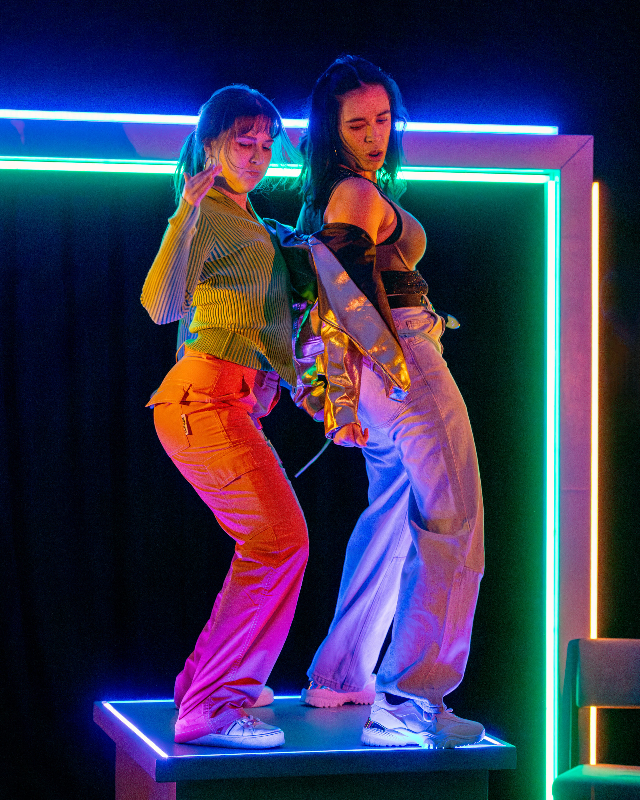 Two young women dancing on a table with neon behind