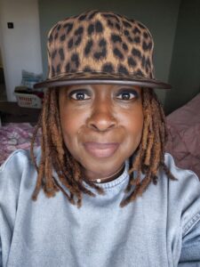 Joanne with small dreadlocks and a leopard skin baseball cap