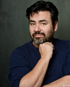 Charles resting on his hand and half smiling to camera