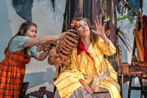 A woman roped to a tree and a woman with a puppet hen