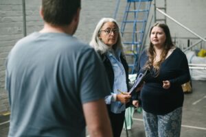 Three people rehearsing a warehouse space. 