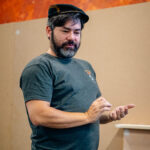 A man in a railway worker's hat pretending to check a passport