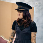 a woman in a ticket inspector's hat looking grumpy