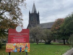 A church with spire with a banner in front advertising The Story Forge children's show