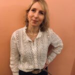 A woman leaning against a peach wall