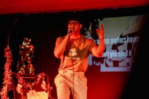 A man rapping in a Santa Must Die t-shirt