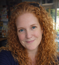 Cate smiling with her long curly red hair framing her face